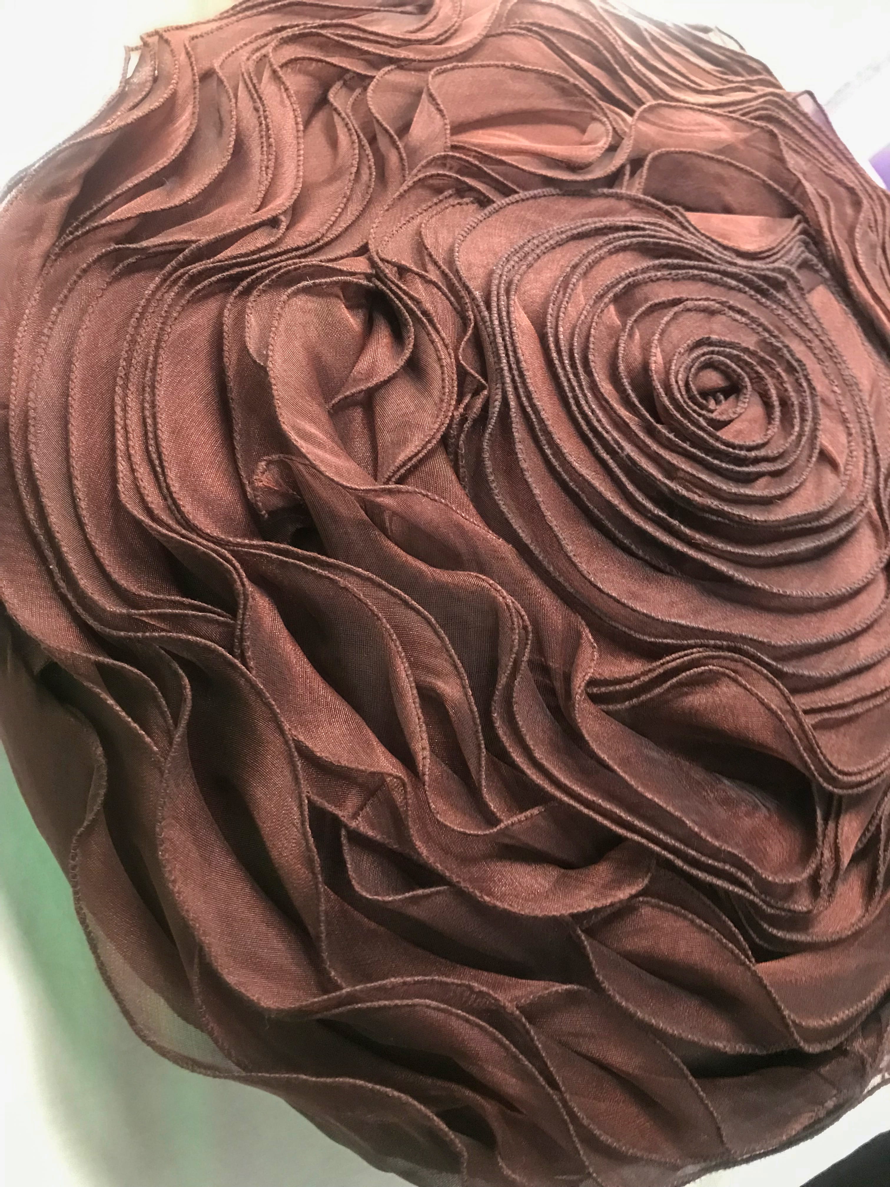 Chocolate brown round rose pillow as part of an earthy autumn arrangement.