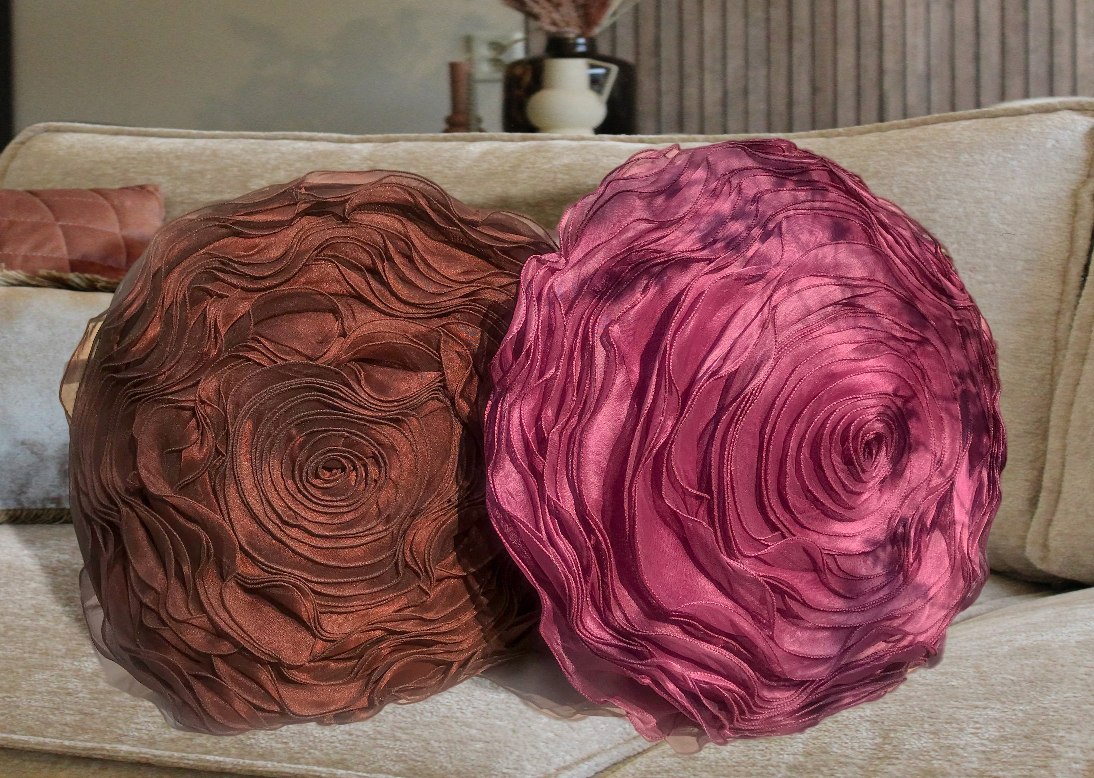 A magenta round 3D rose pillow as a single accent against a neutral sofa.