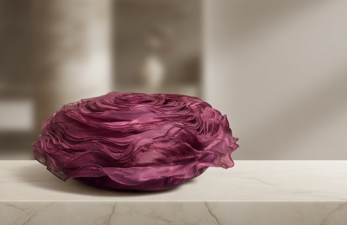 Magenta round 3D rose pillow on a marble console against a neutral background.